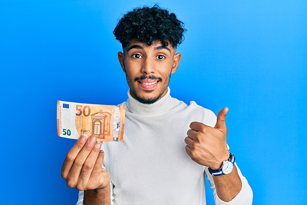 jonge man met geld in zijn hand en steekt duim omhoog